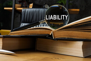 Legal liability concept. Law books and magnifying glass.