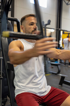 Man in tank top training on chest machine.
