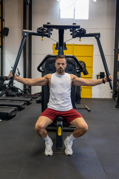 Man in tank top training on chest machine.
