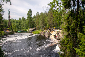 River rapids in a forest landscape with people on a bridge.