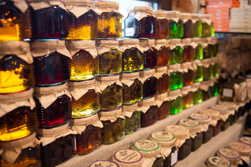 Colorful herbal infusion jars in rows on a market stand.