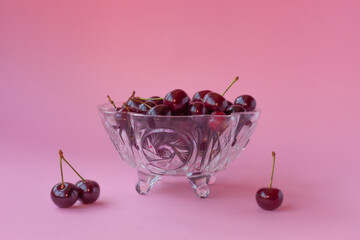 Juicy cherry in a crystal glass on a pink background.
