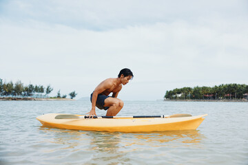 Happy Asian Man Enjoying Active Kayaking Adventure on Tropical Beach
