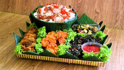 Nasi liwet is a typical Indonesian rice dish cooked with coconut milk, chicken stock and spices, giving the rice a rich, aromatic and savory taste.served on wooden basket