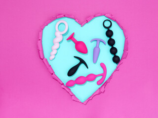 heart shaped hole in pink paper with adult toys for sex games inside