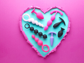 heart shaped hole in pink paper with adult toys for sex games inside