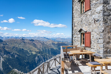 A tranquil scene at the Julius Payer House, showcasing a terrace with wooden benches and tables, affording visitors breathtaking views of the Italian Eastern Alps. Ortles Mountain, Italy