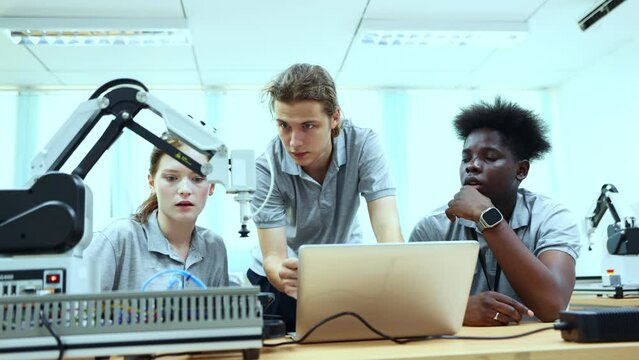 Congratulations hifire two male and female students work together consult information laptop study robot engineers sitting classroom with modern teaching equipment study robot that moves on a table.