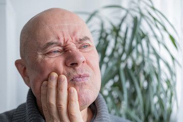 unhappy Senior man, 60, holding painful jaw, agony toothache, pain grimace, suffering from dental problems, sharp pain dental issue, seeking relief