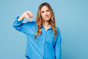 Young sad dissatisfied mad woman she wearing shirt casual clothes showing thumb down dislike...