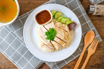 Chicken and rice with coriander and cucumber with sauce and soup in a white plate, hainanese chicken rice, thai called khao man gai, asian food, thai food