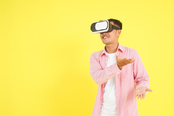 Isolated man in pink shirt wearing a VR headset, presentation and interaction with gesturing hands, standing against a light yellow background. Technology, futuristic, modern innovation concepts