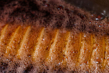 crispy salty fried Tornado Potato spiral chips on a stick cooking in boiling oil
