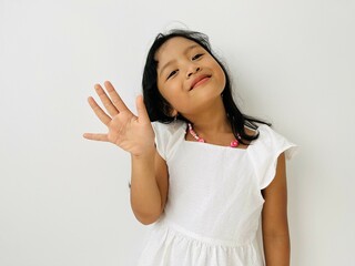 Happy cute Asian little vlogger waving hand saying hello hi looking at camera talking to webcam, smiling kid child girl making online video call recording © Siti Fatonah