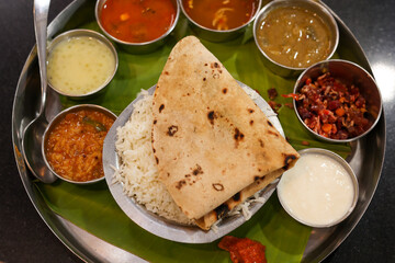 Indian vegetarian platter Thali meals. Having paneer butter masala dal makhani flat bread or naan and rice served in a steel plate and banana leaf Tamil Nadu, Bangalore Karnataka India.