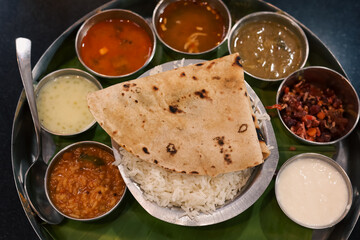 Indian vegetarian platter Thali meals. Having paneer butter masala dal makhani flat bread or naan and rice served in a steel plate and banana leaf Tamil Nadu, Bangalore Karnataka India.