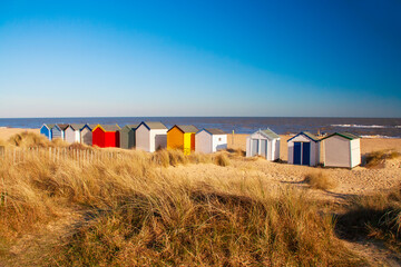 Wooden beach huts in the sand dunes on Southwold beach Suffolk