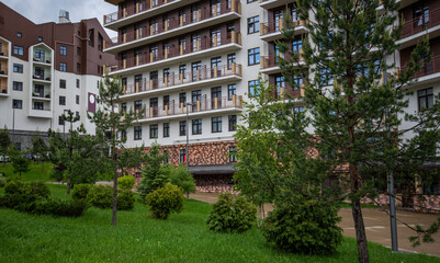 Nestled in a lush green setting, this modern apartment complex stands with its balconies overlooking young pines, offering a blend of urban living and natural tranquility.
