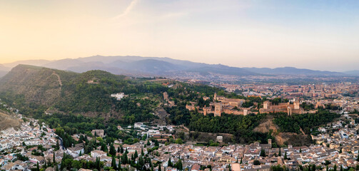 Obraz premium The Alhambra, perched majestically atop a hill in Granada, Spain, bathes in the ethereal beauty of a sunrise