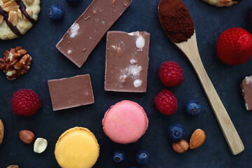 Macarons, chocolate, cookies, berries and various nuts on dark blue background. Top view.