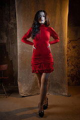 Naklejka premium A femme fatale in a red dress. Attractive brunette in an elegant dress, with a cutout on the back.