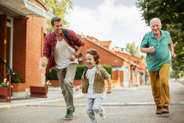 Obraz premium Three generations of family men walking and laughing together outdoors