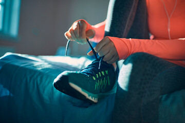 Woman tying running shoes at home before workout