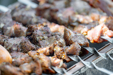 Fried meat strung on skewers is fried over an open fire on a grill.