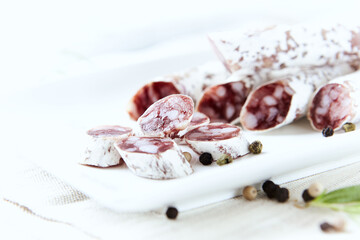 Sliced french salami with fresh rosemary on white background. Copy space.