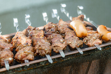 Fried meat strung on skewers is fried over an open fire on a grill.