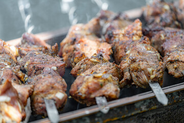 Fried meat strung on skewers is fried over an open fire on a grill.