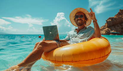 Obraz premium A man is sitting in a yellow inflatable raft on a beach, holding a laptop