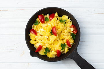 Healthy vegetarian breakfast . Scrambled eggs in pan with cherry tomatoes and parsley