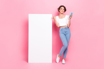 Full length photo of adorable funny girl dressed white top reading modern device thumb empty space isolated pink color background