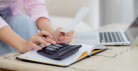 Closeup hands of woman calculating finance household with calculator on desk at home, girl checking bill for saving and planning expenses, debt and loan, tax and accounting, business and financial.