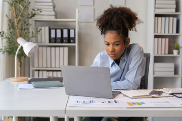 Female Entrepreneur. Cheerful African American Businesswoman Working On document and Laptop In Modern Office. Empty Space