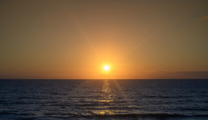Warm waves of the Mediterranean sea and a sandy beach at sunrise