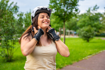 Portrait of roller skater woman putting on helmet in inline skates before rollerblading in park....
