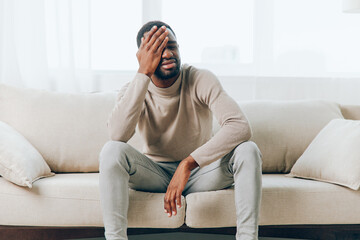 Tired and Stressed African American Man with Headache on Couch at Home Health Issues and Emotional Strain Concept