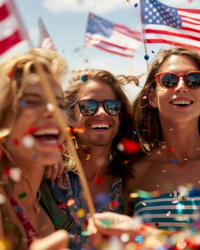 Three friends celebrate with flags, confetti, and sunglasses, enjoying a festive, patriotic event under a sunny sky.
