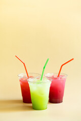 Colored summer freshness lemonades on beige background angle view