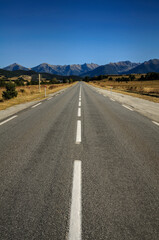 Naklejka premium Straight road from La Quillane to Les Angles (France). At the background, some mountains from Pyrenees Orientales