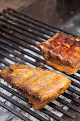 Marinated pork ribs are cooked on the coals of a barbecue