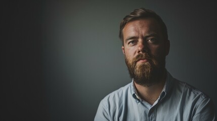 Obraz premium a man with a beard and a blue shirt looking at the camera with a serious look on his face