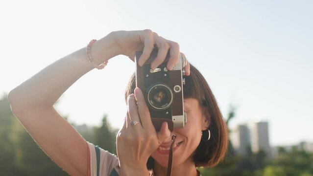 young girl with a camera. Fashionable and attractive beautiful woman with analog film camera takes photos during sunset, 
creates content.  travel and vacation.