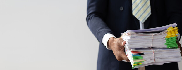 Businessman hands working in Stacks of paper files for searching and checking unfinished document achieves on folders papers at busy work desk office.