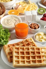 Tasty breakfast. Belgian waffles and other food on light table, closeup
