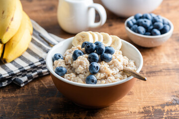 Breakfast bowl with oatmeal, blueberries, and bananas for a healthy start on a wooden table background