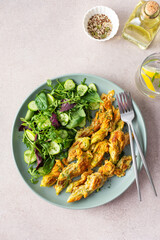 Fried zucchini flowers in batter and mix salad with cucumbers, top view