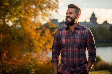 Portrait of a jovial man in his 30s dressed in a relaxed flannel shirt isolated on vibrant city park